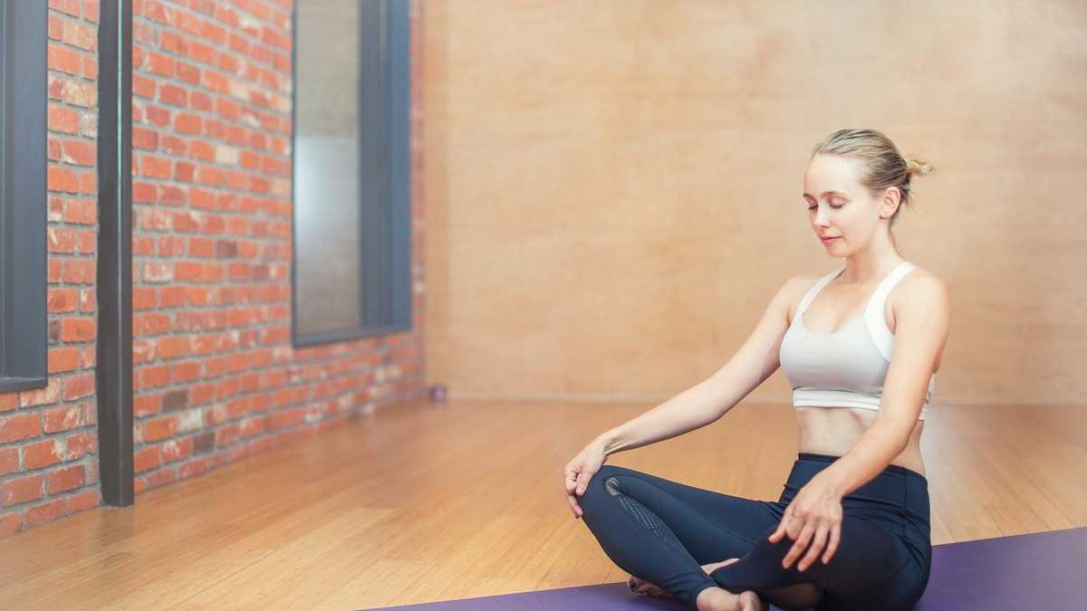 Pratiquante de yoga sur tapis en posture douce, illustrant les précautions du Hatha Yoga