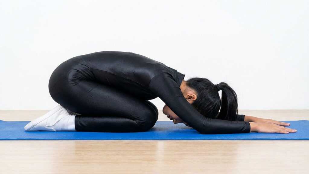personne pratiquant la posture de l’enfant sur un tapis de yoga pour relâcher doucement le dos