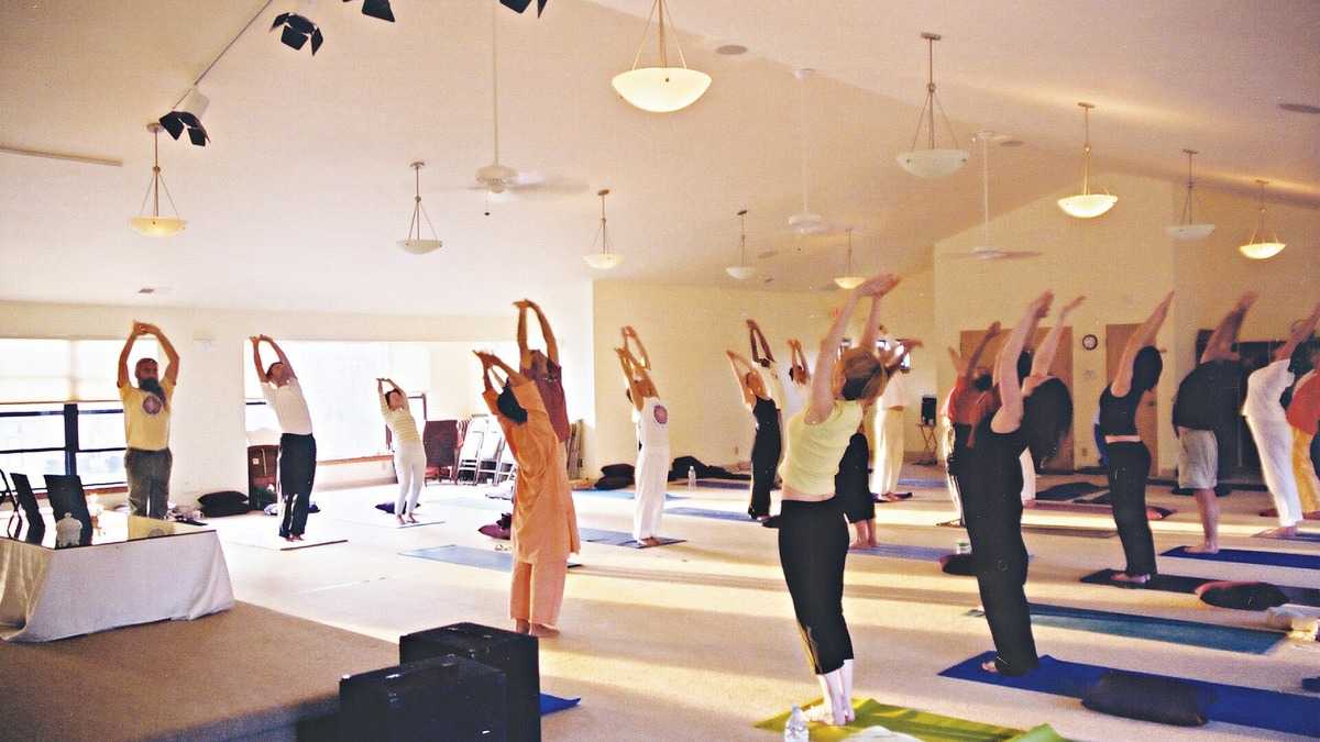 Cours de yoga avec plusieurs postures sur tapis pour illustrer une liste PDF des 108 postures du yoga